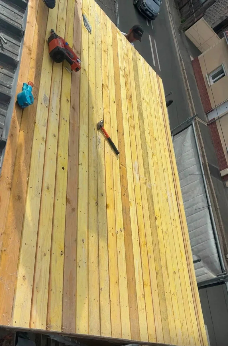 Liteaux et voliges en bois neuf vus du dessus, visseuse et marteau posés dessus